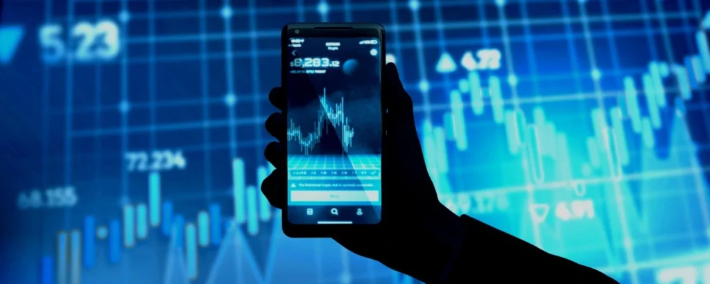 Hand holding a smartphone with financial charts on screen, representing the digitalization and growth of neobanks versus banking.