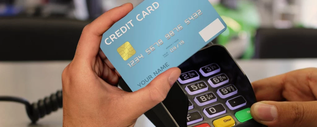 Hands holding a credit card near a POS terminal to complete a transaction, representing fast and secure B2B payment solutions in the fintech environment.