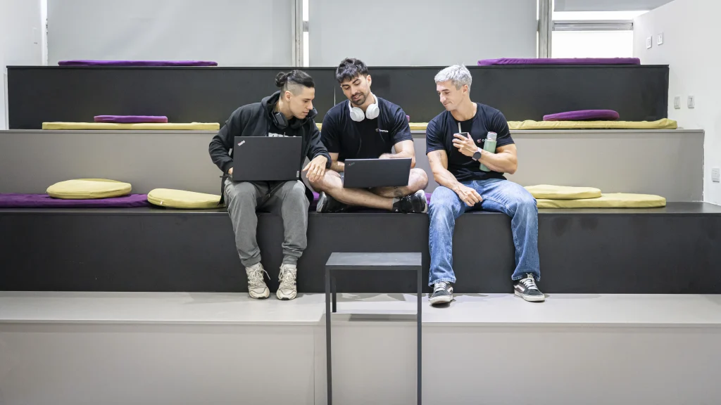 A professional photograph showing Crombie team members in a focused collaborative discussion around a workstation.