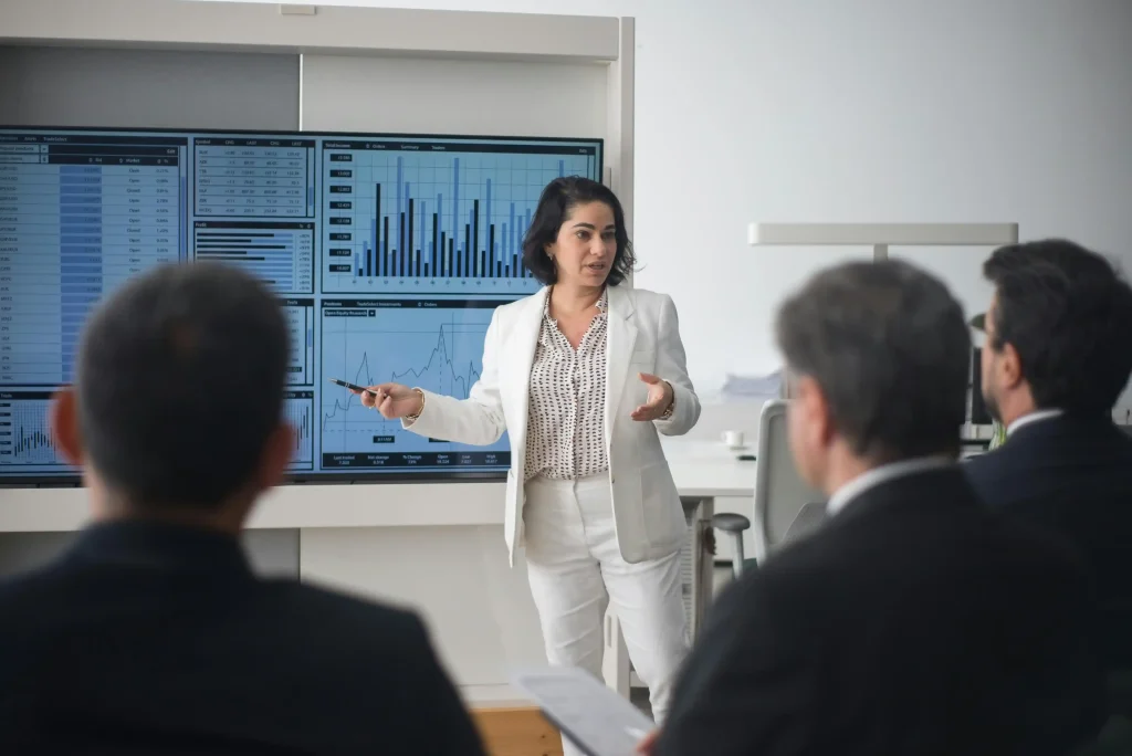 Business leader presenting data dashboards and market trends to executives, illustrating AI forecast strategies for decision-making.