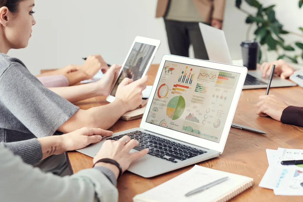 Business team analyzing charts and data dashboards on laptops and tablets, representing data normalization, system integration, and data-driven decision-making.